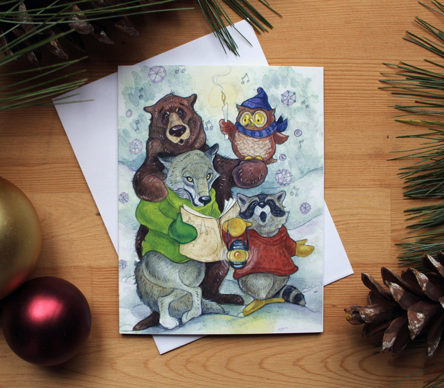 A illustrated christmas card of a group of animals. A bear, a wolf, a raccoon and an owl join together to sing christmas carols