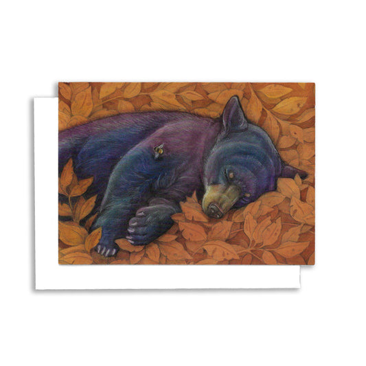 an illustrated greeting card showing a black bear sleeping with a rust coloured stylized leaf background. A bee flies by.