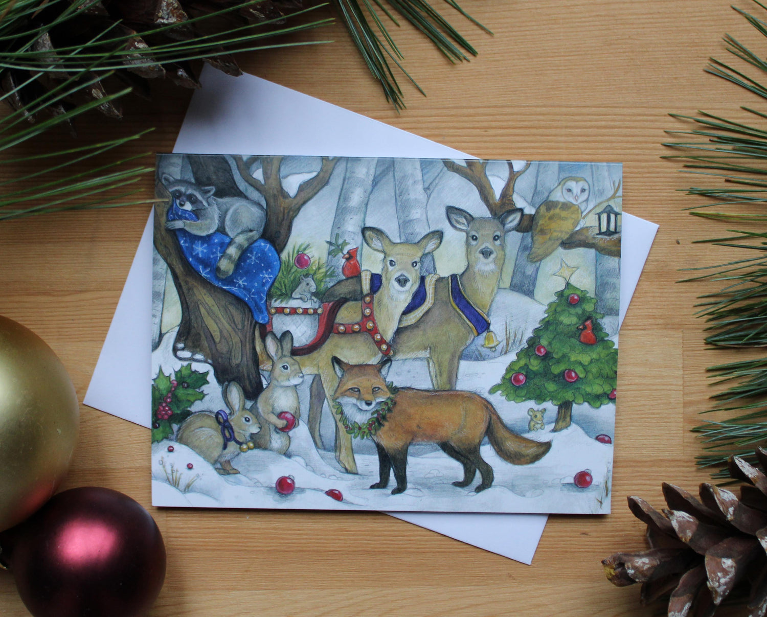 illustrated christmas card of forest animals gathered together to celebrate the holiday season.