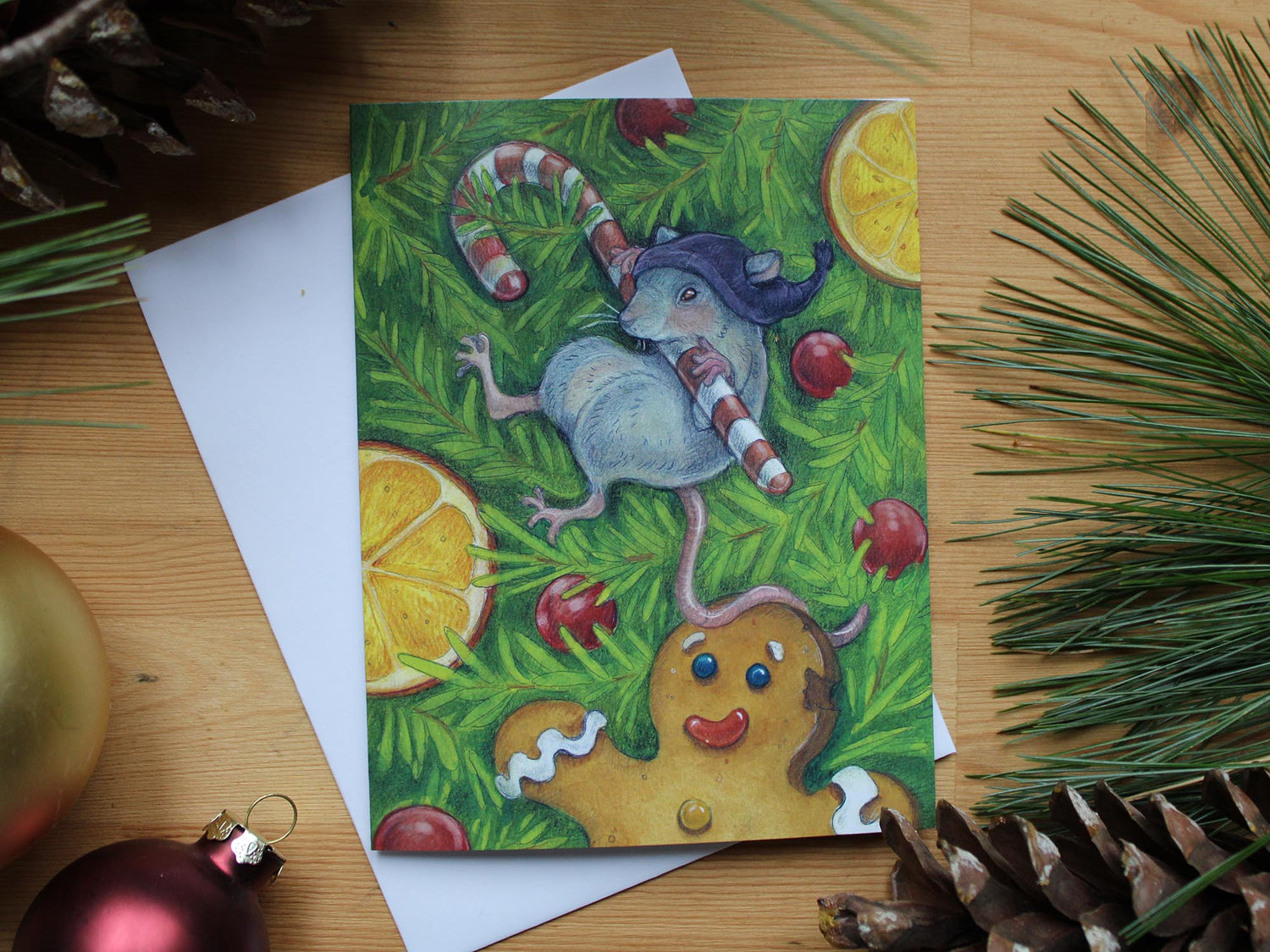 illustrated christmas cards of little mouse clinging to candy cane hanging in christmas tree. Decorated with cranberries , orange slices and gingerbread man.