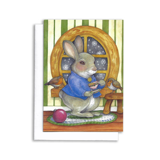 An illustrated Christmas themed card showing Peter Rabbit drinking tea. There are two robin friends with him.